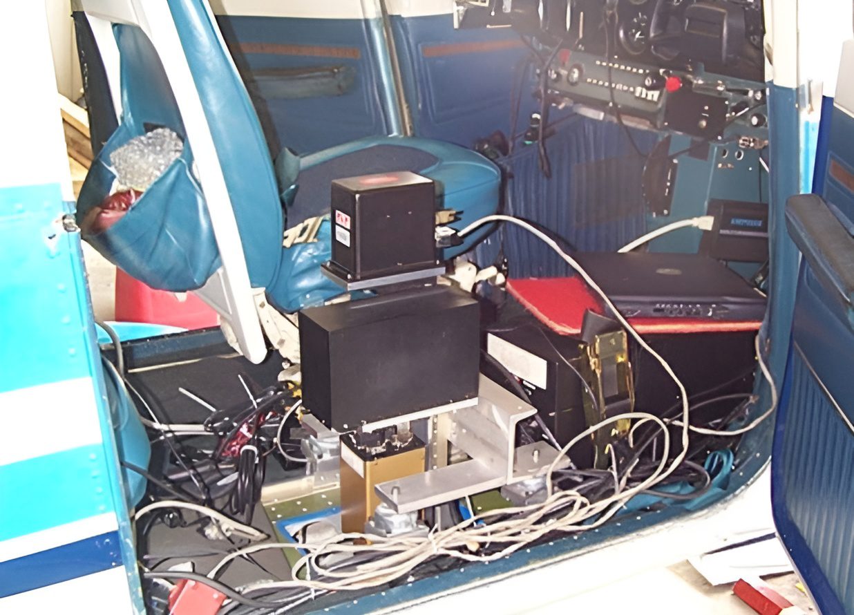 A blue car with many wires and electronics on the floor.